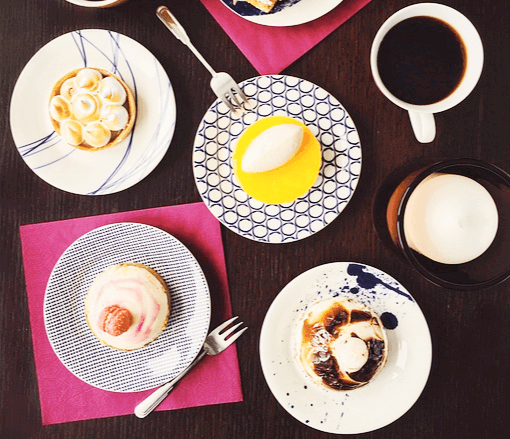 나무 식탁 위에 블랙 커피와 아이스크림, 컵케이크 등 각종 디저트가 있다.