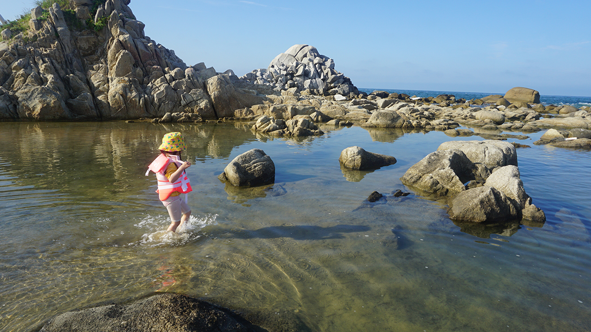 바닷물이 만든 얕은 물웅덩이에서 아이가 물장구 치는 모습