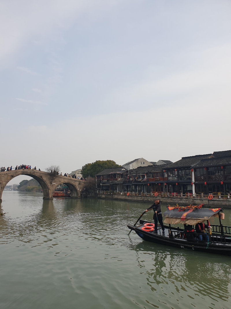 멀리 사람들이 방생교를 건너고 있다. 앞에는 사공이 노를 젓고 있다.