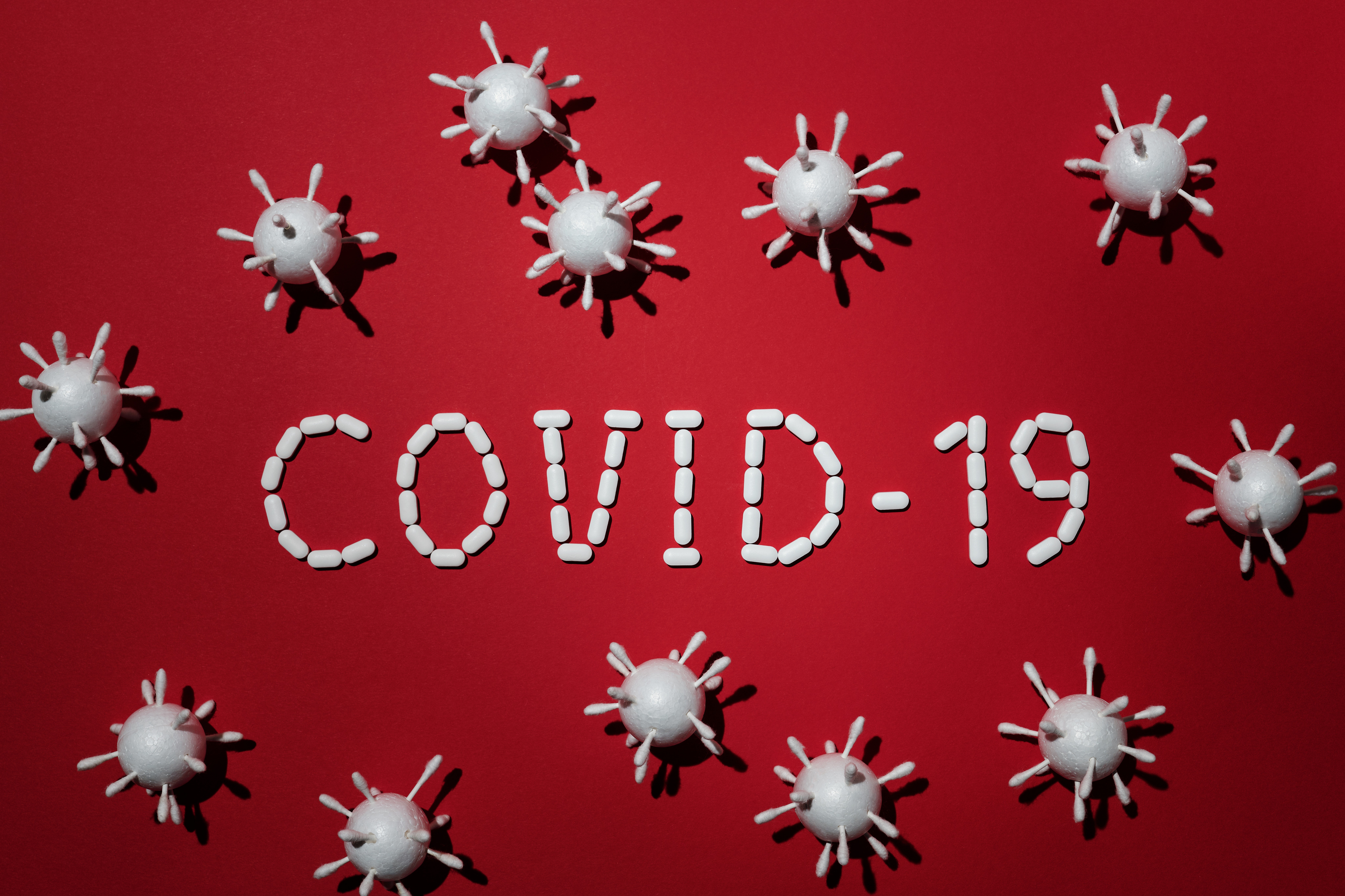빨간색 배경위에 스티로폼과 면봉으로 만든 세포모형&#44; 알약으로 구성된 COVID-19 문자