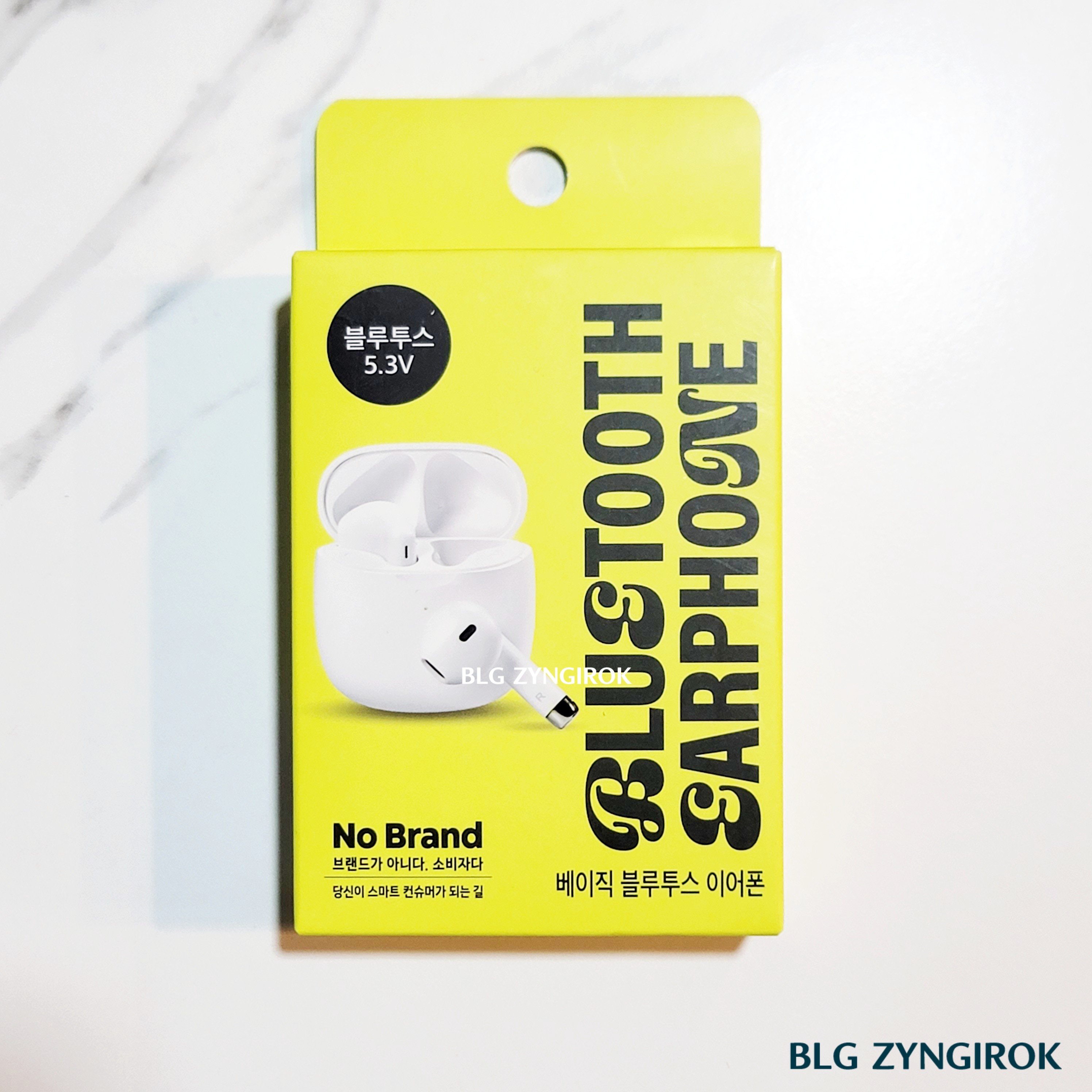 노브랜드 전자기기 : 무선 이어폰 상자가 테이블 위에 놓여있다.