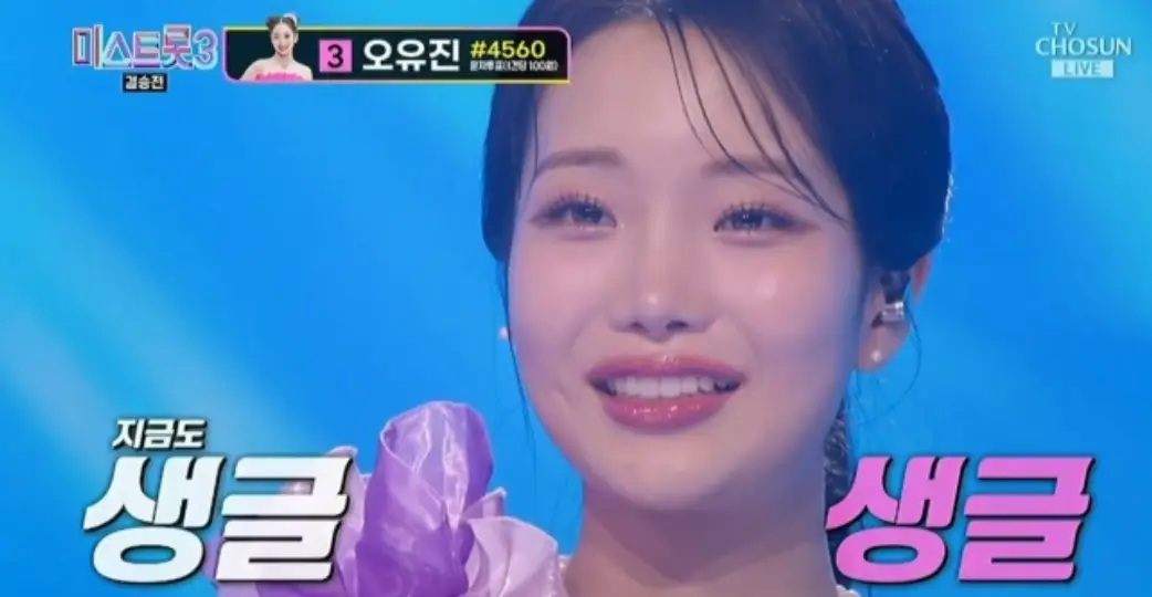 미스트롯3-
파란색 무대배경 보라색 머리를 뒤로 하나로 묶은채 눈물을 글썽이며 미소짓는 김소연