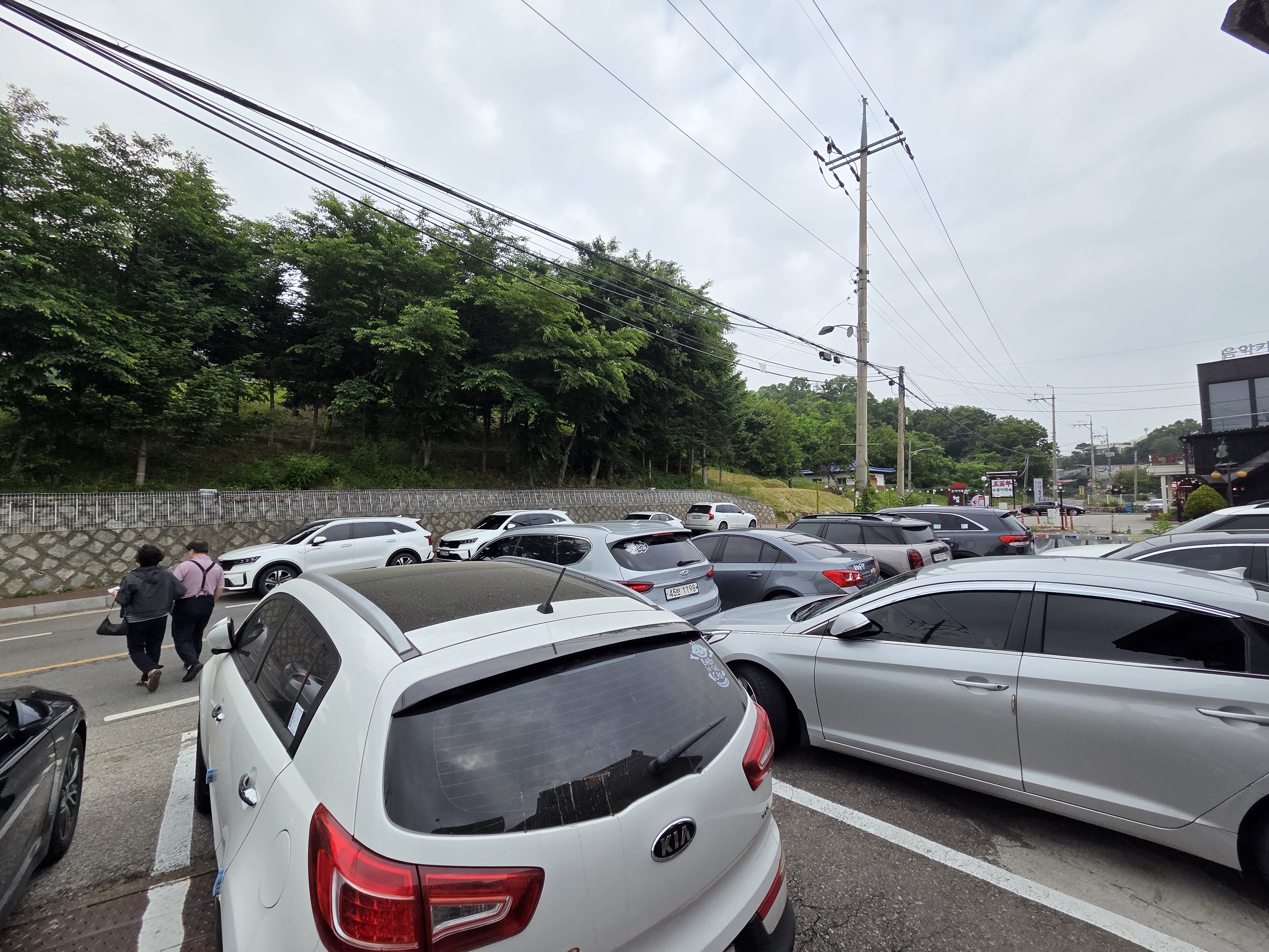 식당 바로 앞 주차장과 맞은편 갓길 평행 주차장에 차량이 가득 차 있는 모습