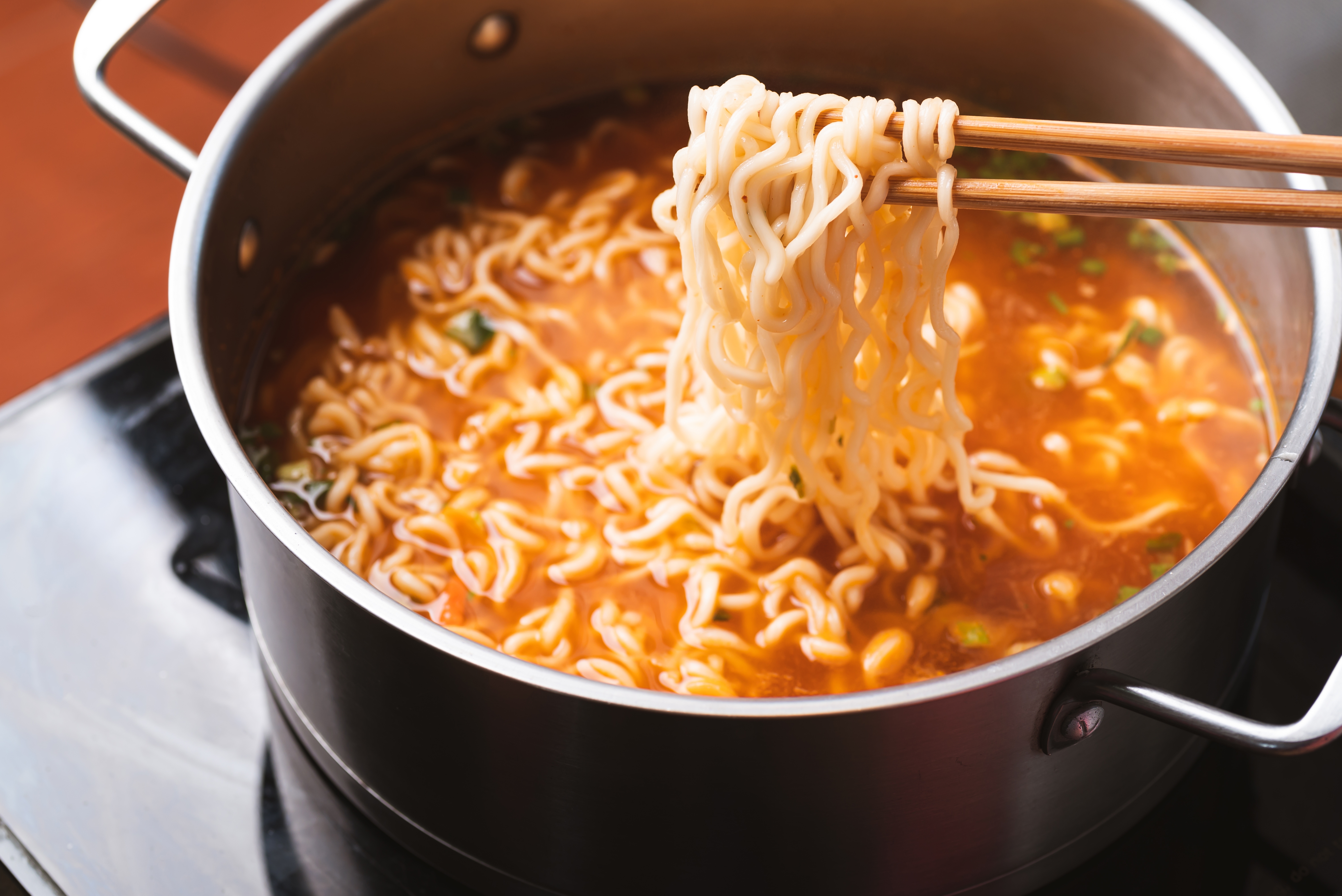 끓는 냄비 속 라면을 젓가락으로 집어올리는 자취생 간편식 이미지