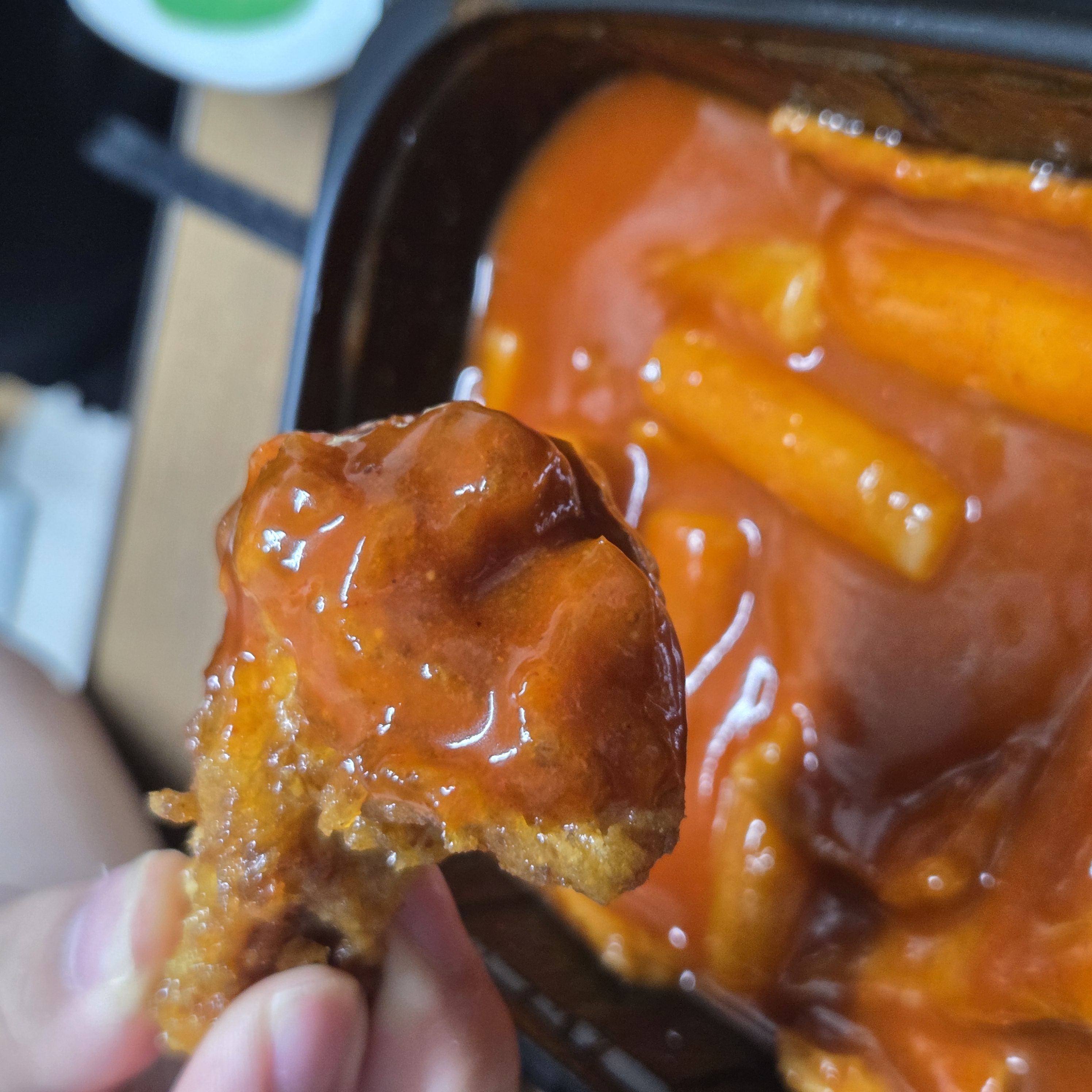 떡볶이 국물에 적신 허니콤보 치킨을 손으로 집은 모습, 단짠 조합의 대표 장면