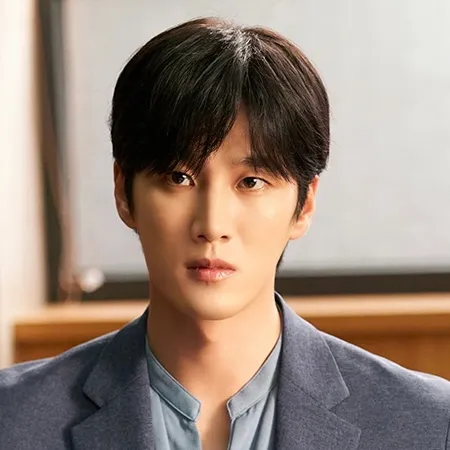 어느 사무실을 배경으로 양복 자켓을 입고 전면을 바라보는 문서하