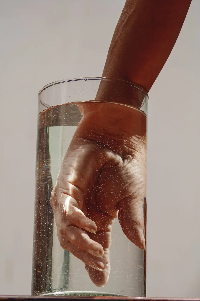 한랭질환 - 투명색 물이 가득 담긴 물병에 오른손을 넣은 이미지