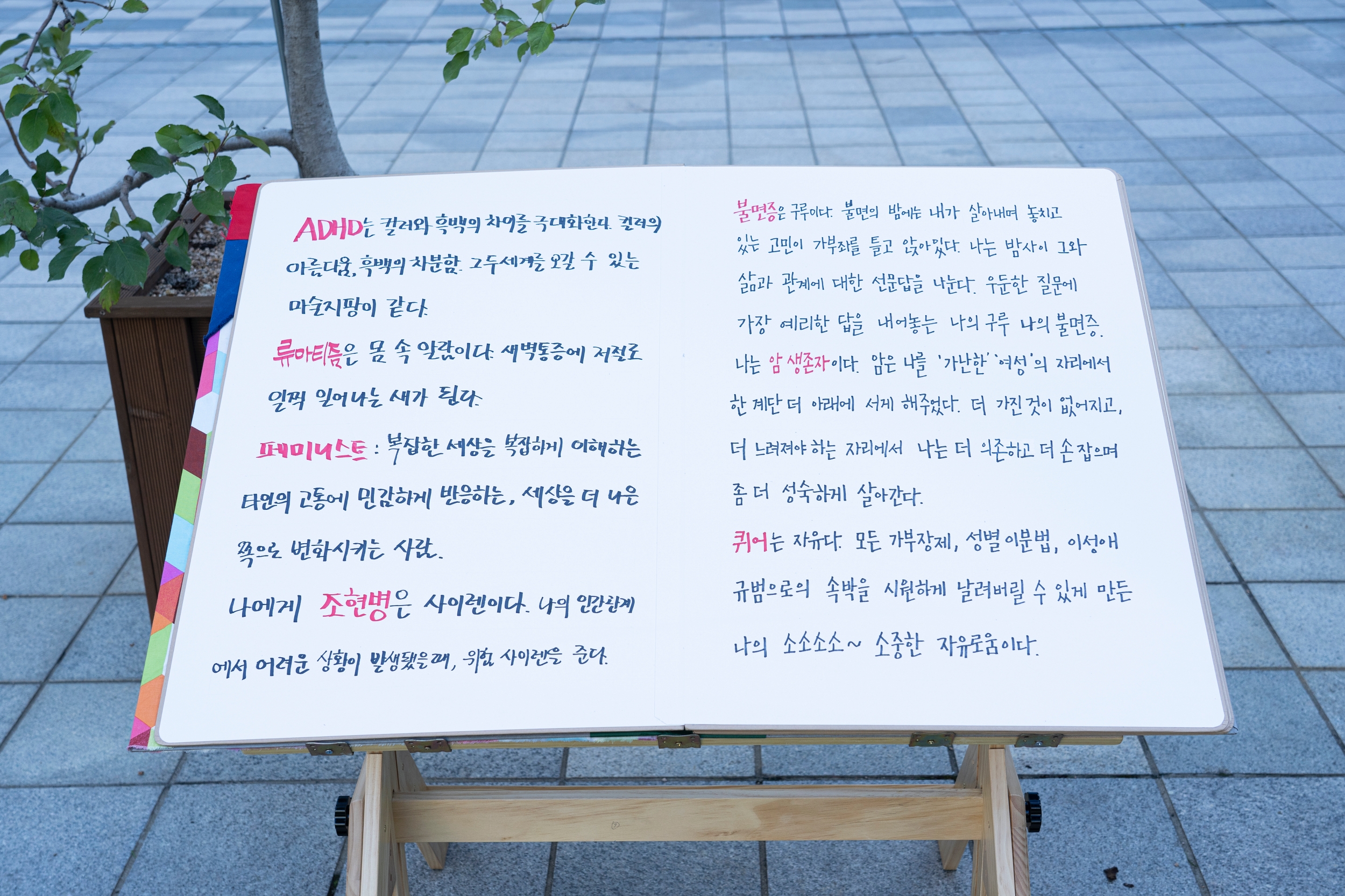 거대한 책 모형에 &lt;나만의 정체성 사전&gt; 내용들이 적혀 있다.