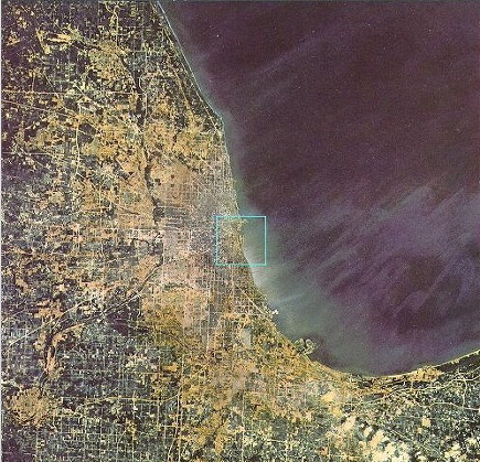 지상 100킬로미터 상공에서 바라본 시카고와 그 주변 지역. 미시간 호수가 오른쪽에 넓게 펼쳐져 있으며, 왼쪽에는 시카고를 중심으로 도시와 교외 지역이 격자형 도로망을 따라 퍼져 있다. 도시의 윤곽은 흐릿해지고, 인간 활동의 흔적은 점과 선의 집합으로 변해간다. 거대한 호수와 육지가 만나는 경계가 뚜렷하게 드러나며, 인간의 흔적이 점차 축소되는 시점이다.