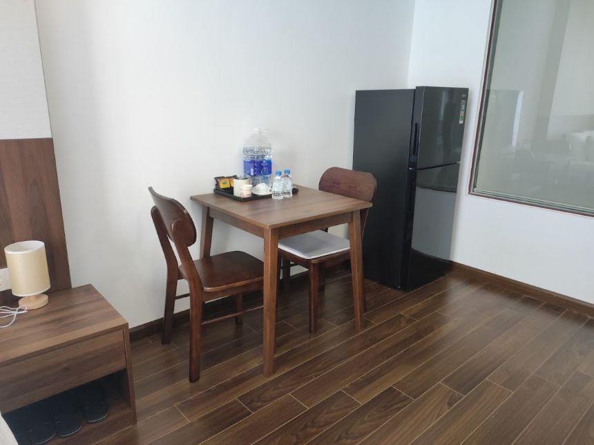 다낭 젠 로터스 호텔 아파트먼트 객실의 2인용 식탁과 대형 투도어 냉장고