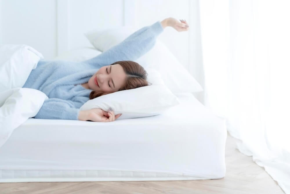 침대에서 기지개를 피고 있는 여성