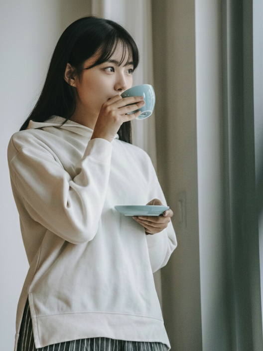 커피잔을 한 손에 들고 커피를 마시고 있는 여인
