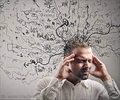 남자가 양 관자놀이에 손을 대고 있고 배경의 하얀벽에는 이리저리 낙서가 되어 있다