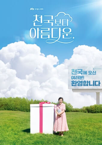 드라마 천국보다 아름다운의 여주인공 김혜자 배우가 뭉게구름 하늘과 녹색 잔디밭에 있는 큰 선물박스 옆에, 분홍색 드레스를 입고 포즈를 취하고 있다.