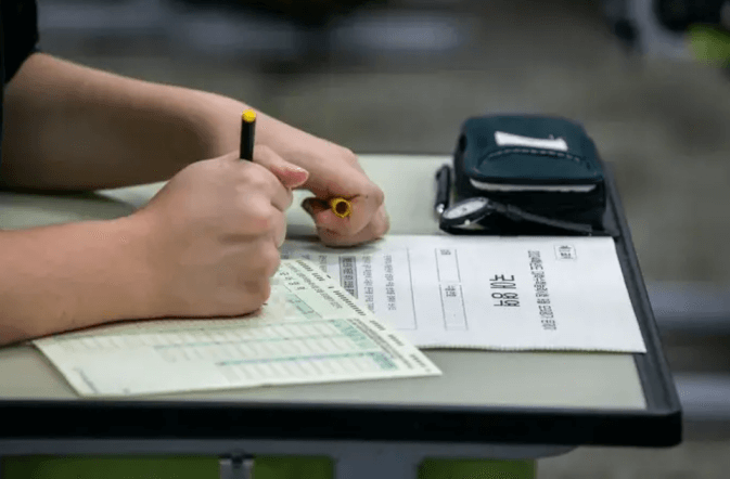 입시제도- 흰색시험지 위 검은색 펜을 들고있는 손