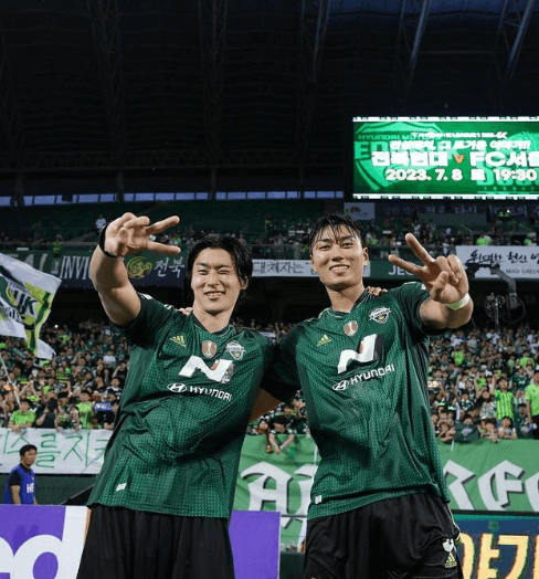 조규성 선수가 경기장에서 동료 선수와 브이 포즈를 취하는 장면