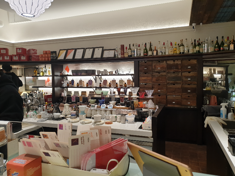 뒷 편으로 드리퍼 등 커피 용품과 술병 그리고 글라스웨어들이 진열되어 있다.