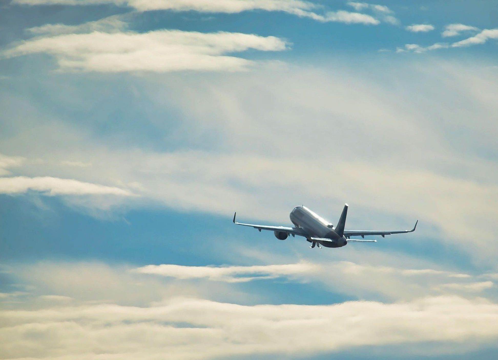 An Airplane Soaring through a Blue Sky Filled with Soft, White Clouds