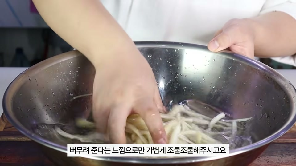 절임물에 도라지를 넣고 조물조물 무치는 장면