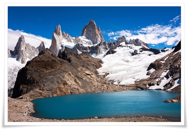 산 정상에 하얗게 흰눈이 덮여있고, 거대하고 날카로운 바위 봉우리들과 청록색 빛깔의 호수가 어우러진 장엄한 자연의 풍경