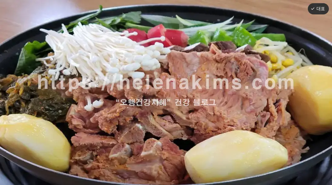 김이 모락모락 피어오르는 먹음직스러운 감자탕이 중앙에 놓여있는 클로즈업 된 이미지.