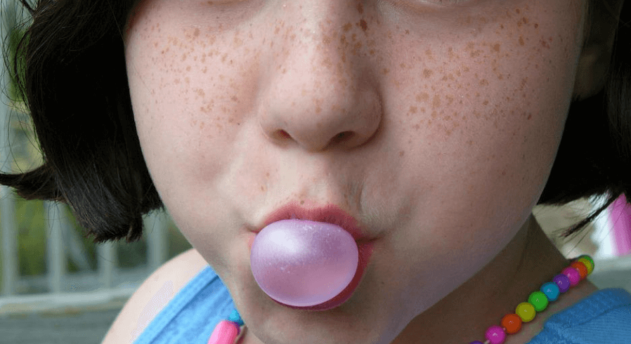소녀가 입으로 풍선껌을 불고 있다