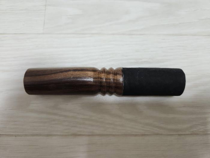 A wooden stick with one end wrapped in suede leather.