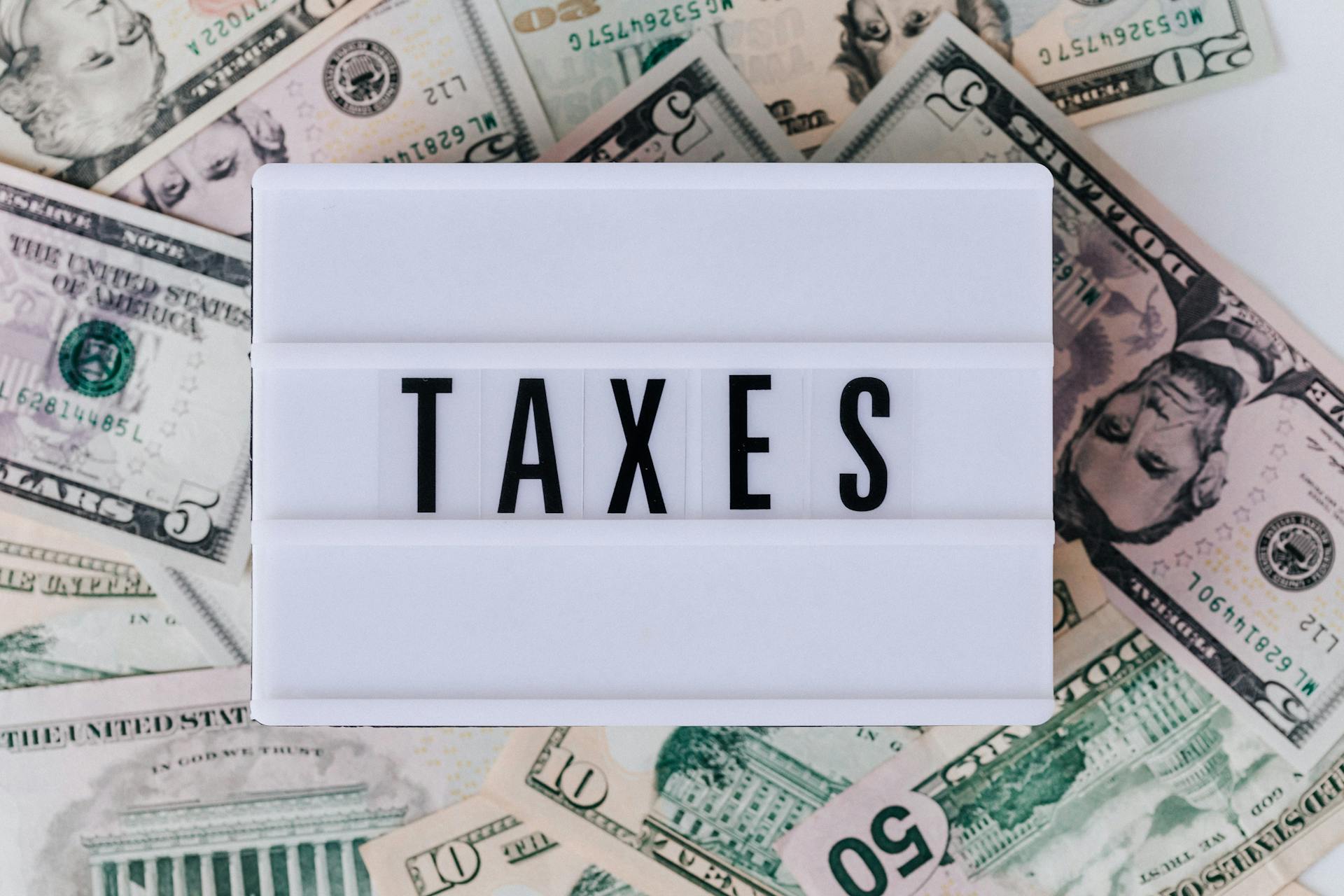 달러들이 놓여진 가운데 TAXES 라고 적혀있는 모습