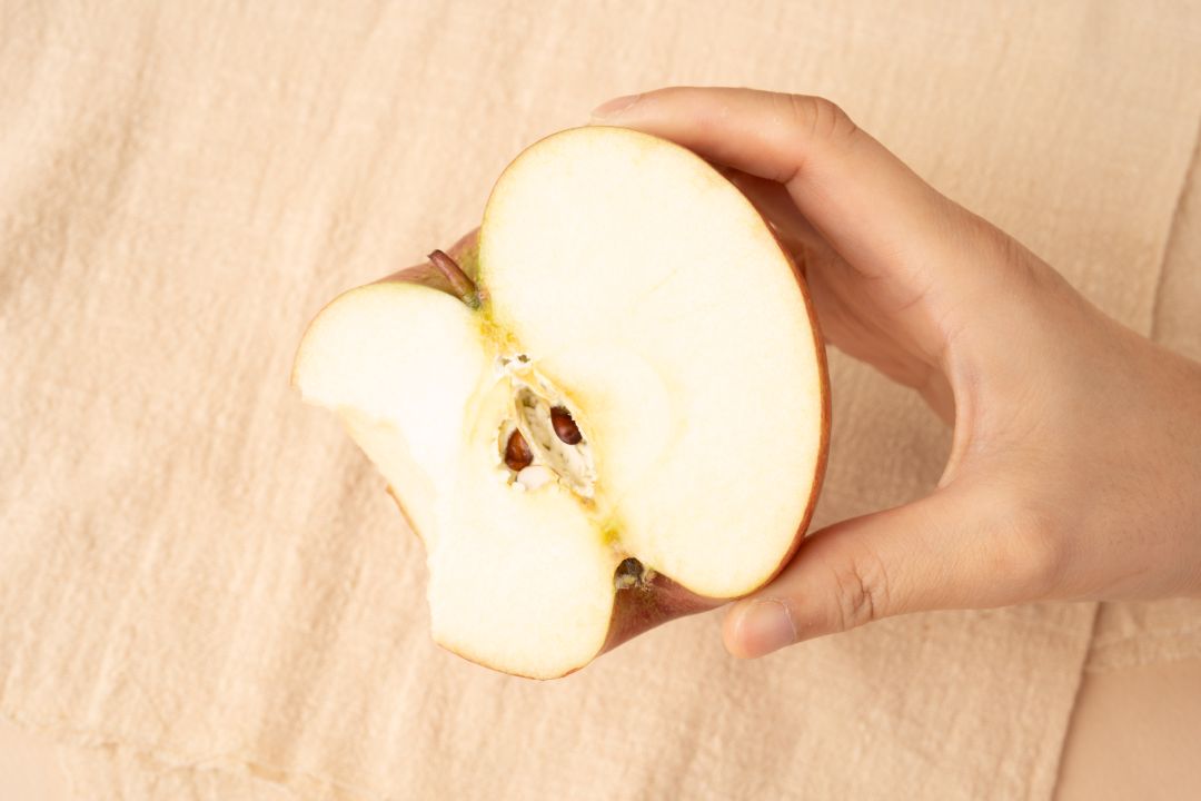 사람의 손에 들려 있는 부사 사과의 반쪽 단면 근접 촬영 사진. 뽀얀 과육과 신선한 질감이 강조된 모습.