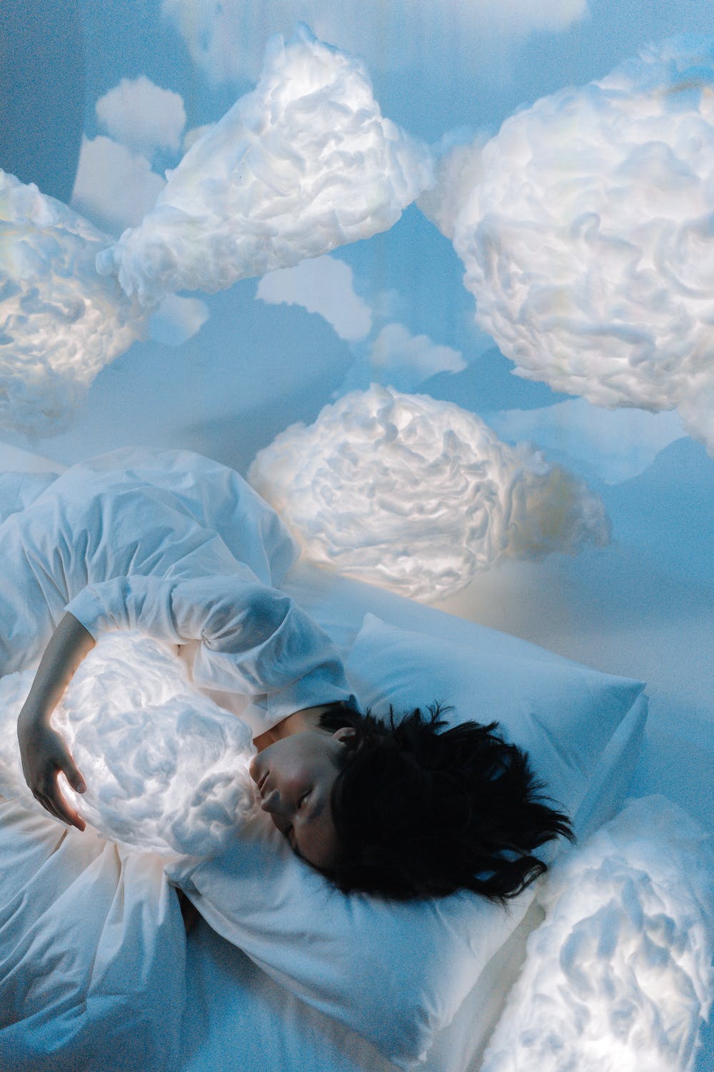 마치 하늘에 있는 듯한 배경과 구름을 끌어안고 자고 있는 여성