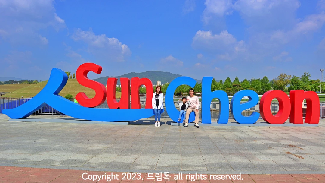 파란색과 빨간색으로 영어로 순천온이라고 적힌 커다란 조형물에서 세사람이 사진을 찍는다.