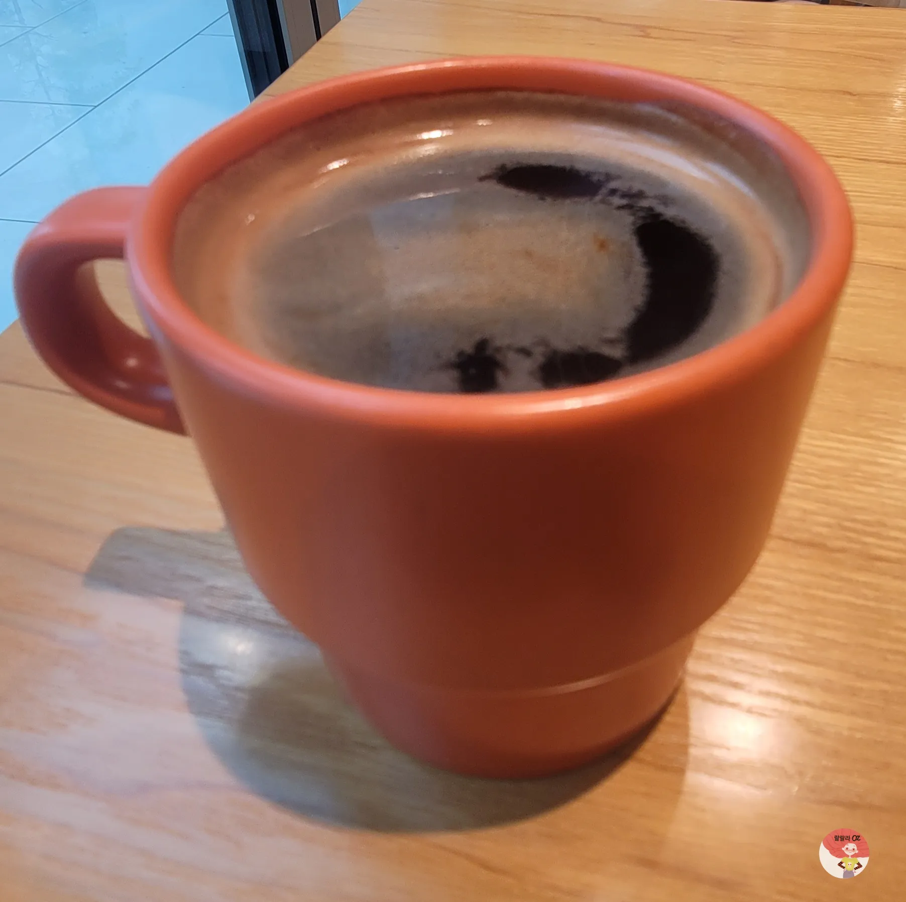오렌지색 머그잔에 담긴 뜨거운 아메리카노&amp;#44; 나무 테이블 위 근접 촬영