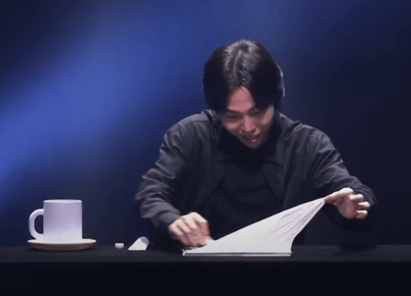 DK 마술사가 즐거운 표정으로 나이프로 스케치북을 한겹씩 자르고 있다.