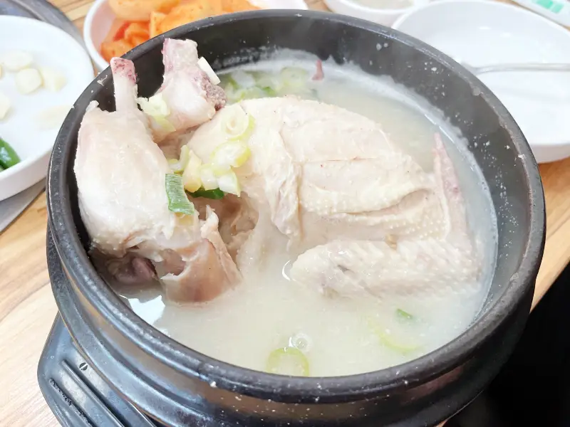 검은색 뚝배기 그릇에 삼계탕이 담겨있는 모습