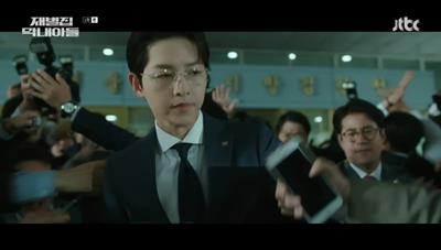 기자들을 제지하면서 회장을 이동시키는 송중기 사진입니다.