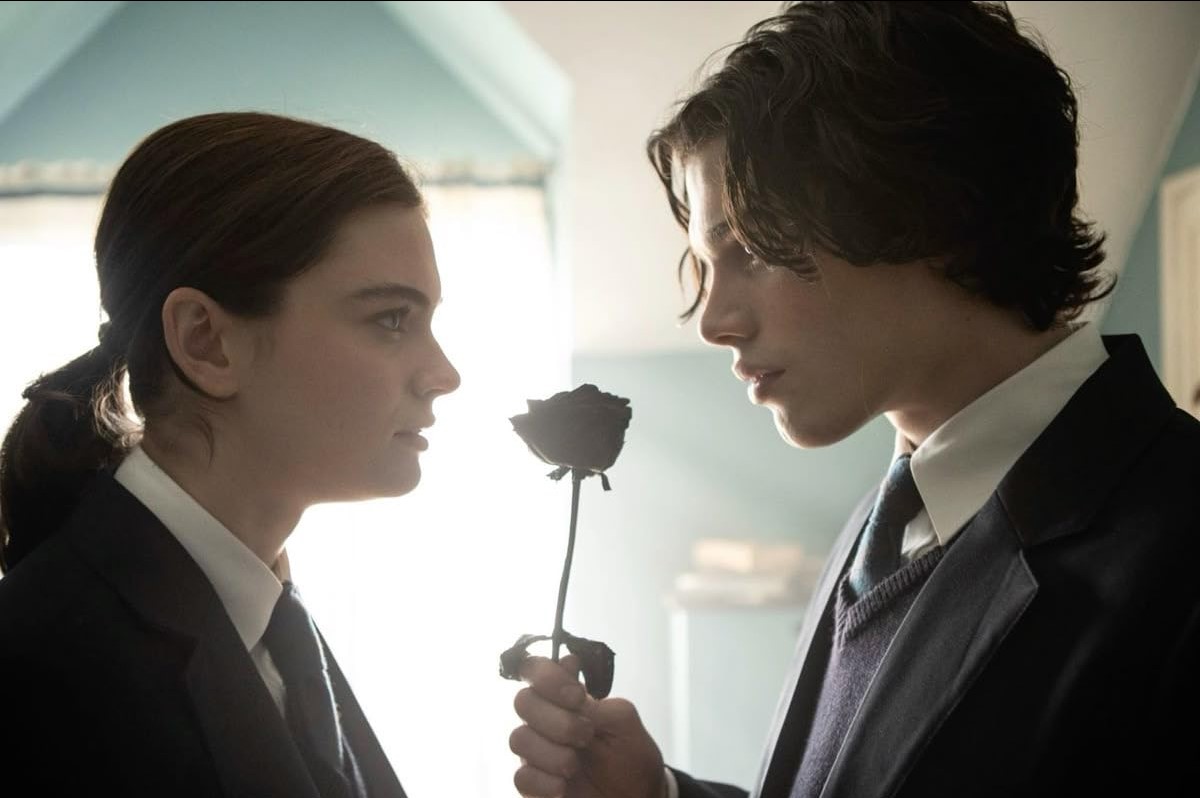 영화 '눈물을 만드는 사람' 속 니카와 리고가 서로를 바라보며 검은 장미를 사이에 둔 장면