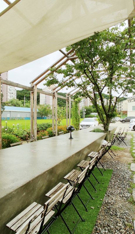 커다랗고 길게 만튼 회색 콘크리트 테이블 카페 문에서 본모습