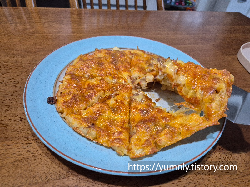 A child's hand taking a slice of the french fry pizza with a server