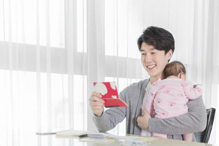 아기를-안고-지급통장을-보며-웃는-아버지