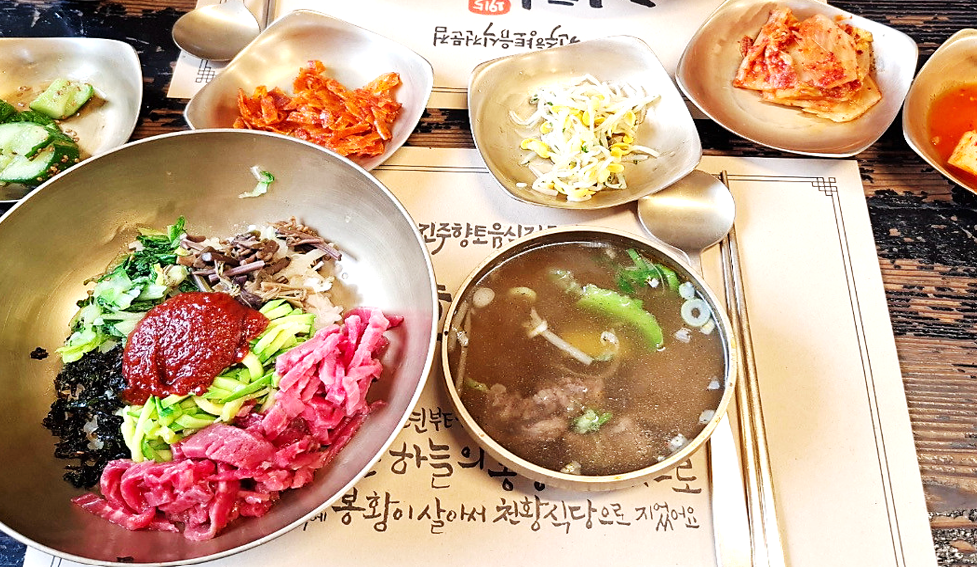 육회비빔밥과 선지를 넣은 소고기국, 각종 밑반찬이 테이블 위에 차려져 있는 모습