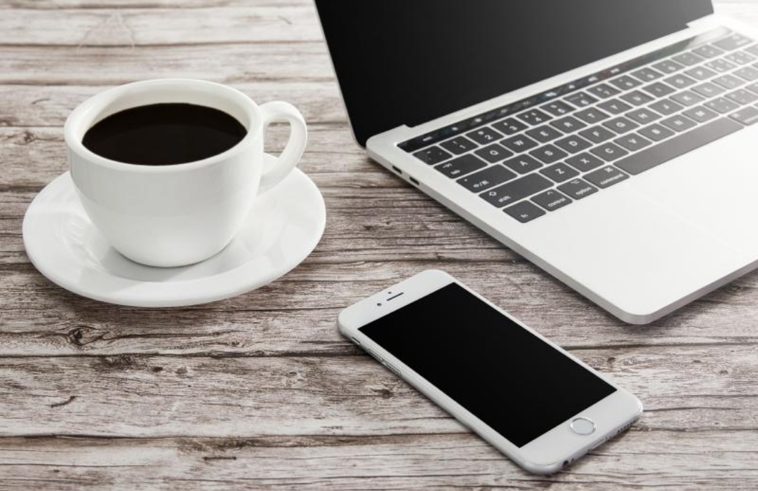 테이블에 커피와 노트북 핸드폰이 놓여있다.