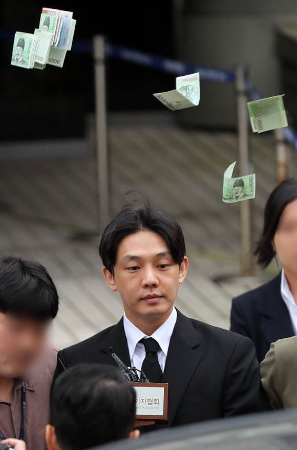 배우 유아인이 21일 서울 서초구 서울중앙지법에서 열린 마약류 관리에 관한 법률 위반 등 혐의 구속 전 피의자 심문(영장실질심사)을 마친 후 대기 장소로 이동하는 중 한 시민이 돈을 뿌리고 있다. [사진=뉴시스]