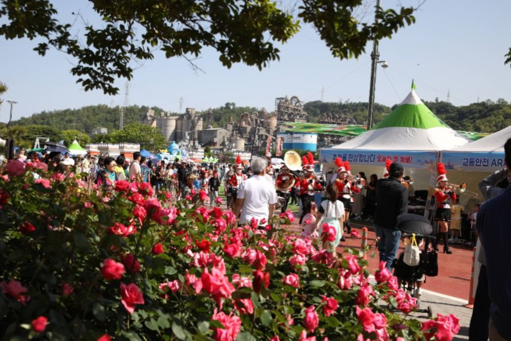 삼척장미축제의 왼쪽에는 많은 장미가 활짝 피어있고, 수많은 사람들로 붐비는 풍경