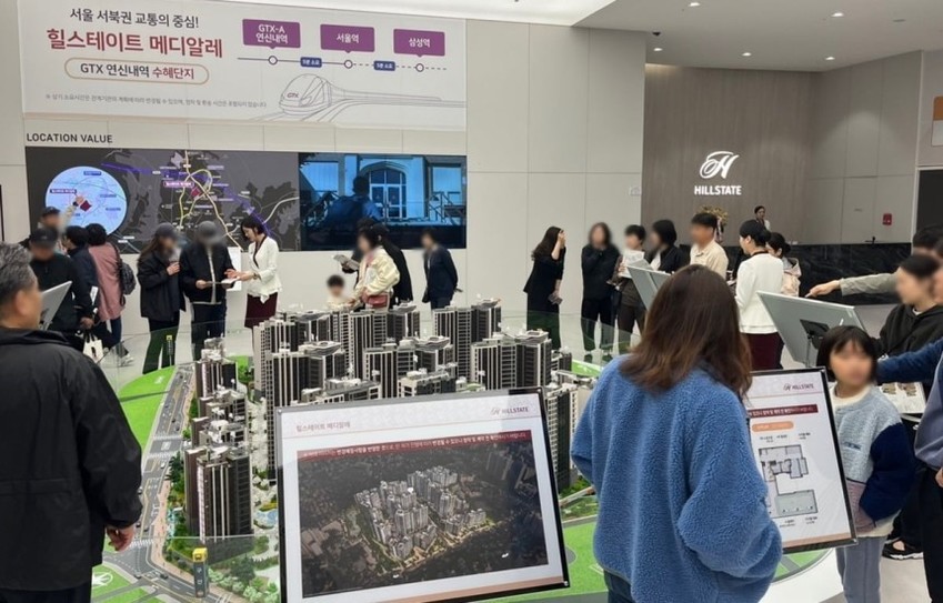 힐스테이트 메디알레 견본주택에서 방문객들이 아파트 모형을 보고 있는 모습.