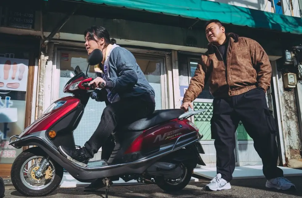 범죄도시-붉은 오토바이를 타고 달리려는 여자의 오토바이를 한손으로 잡고있는 마동석