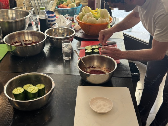 A class participant slicing and prepping cucumbers with cross slits for making stuffed cucumber Kimchi ❘ Un participant coupant des concombres en croix pour la préparation du Kimchi de concombre farci