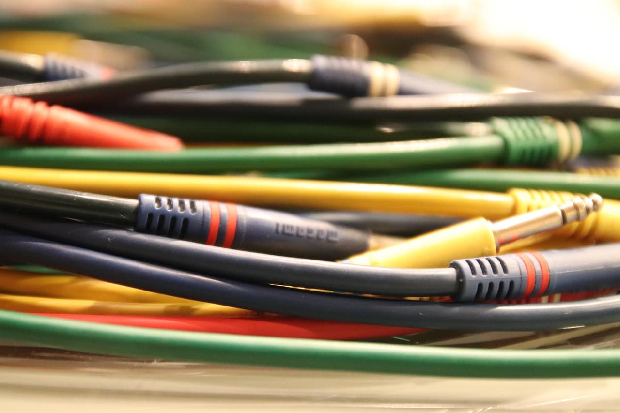 여러 가지 색상의 케이블들이 뒤엉켜 있는 근접 사진이다. 오디오나 전자 장비용 케이블로 보이며&amp;#44; 각 단자 부분이 군데군데 노출되어 있다.