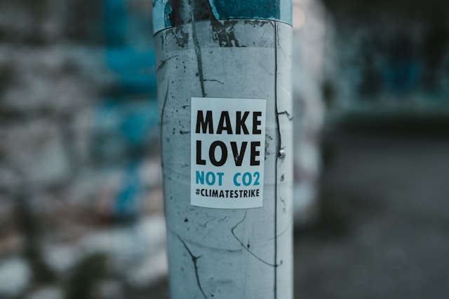 MAKE LOVE NOT CO2 #CLIMATESTRIKE 문구가 적힌 환경 캠페인 스티커, 도시 전봇대에 부착된 모습