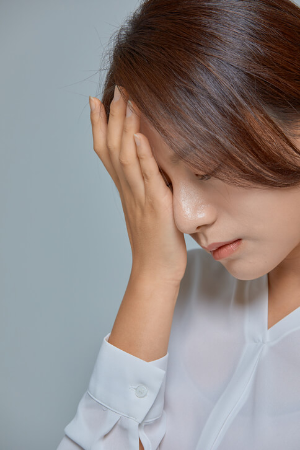 눈이 피로한 듯 눈 부위에 손을 올리고 있는 여성