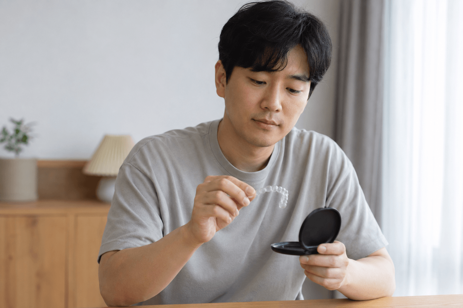 중단한 투명교정 장치와 보관함을 살펴보는 30대 남성